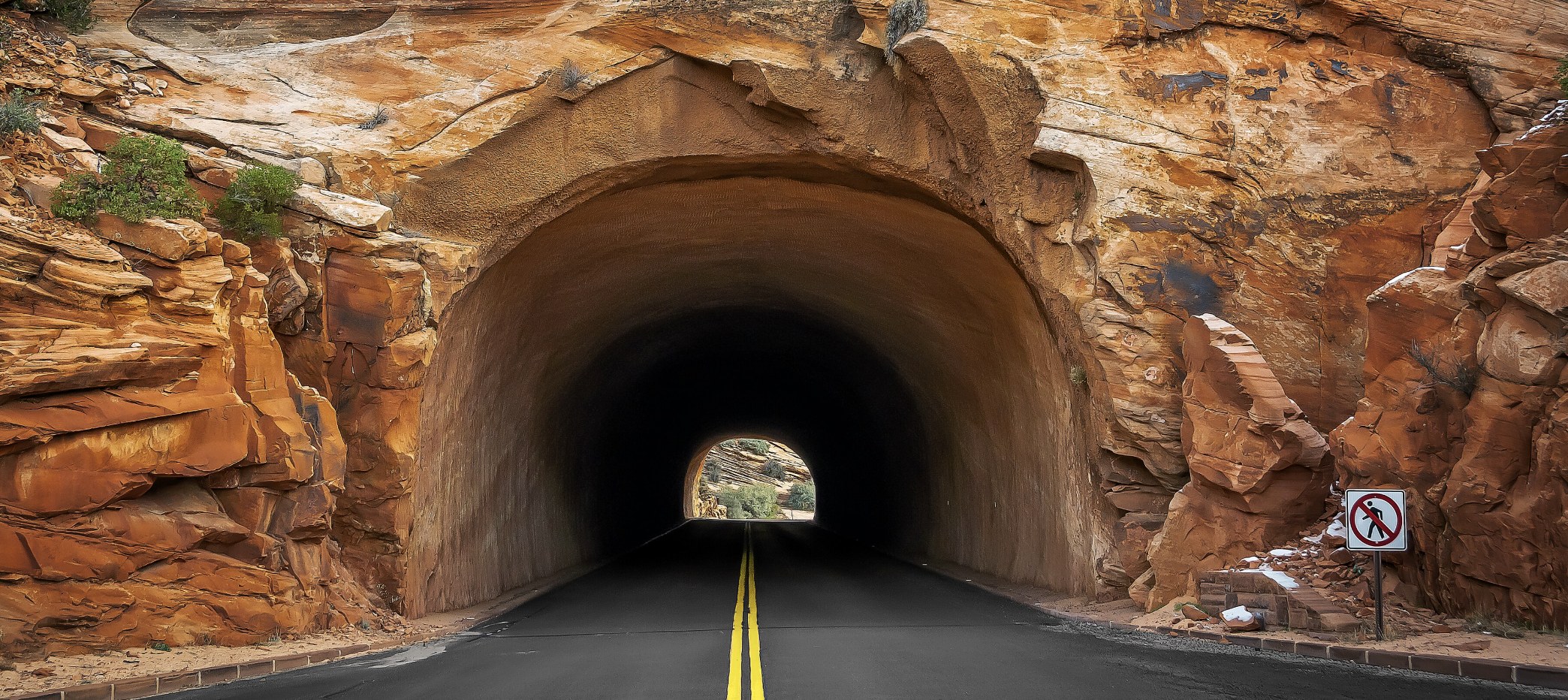 Tunnel Entrance on the Zion Mount Carmel Highway Road tunnel bored into red sandstone on the Zion Mount Carmel Highway with a no pedestrians sign